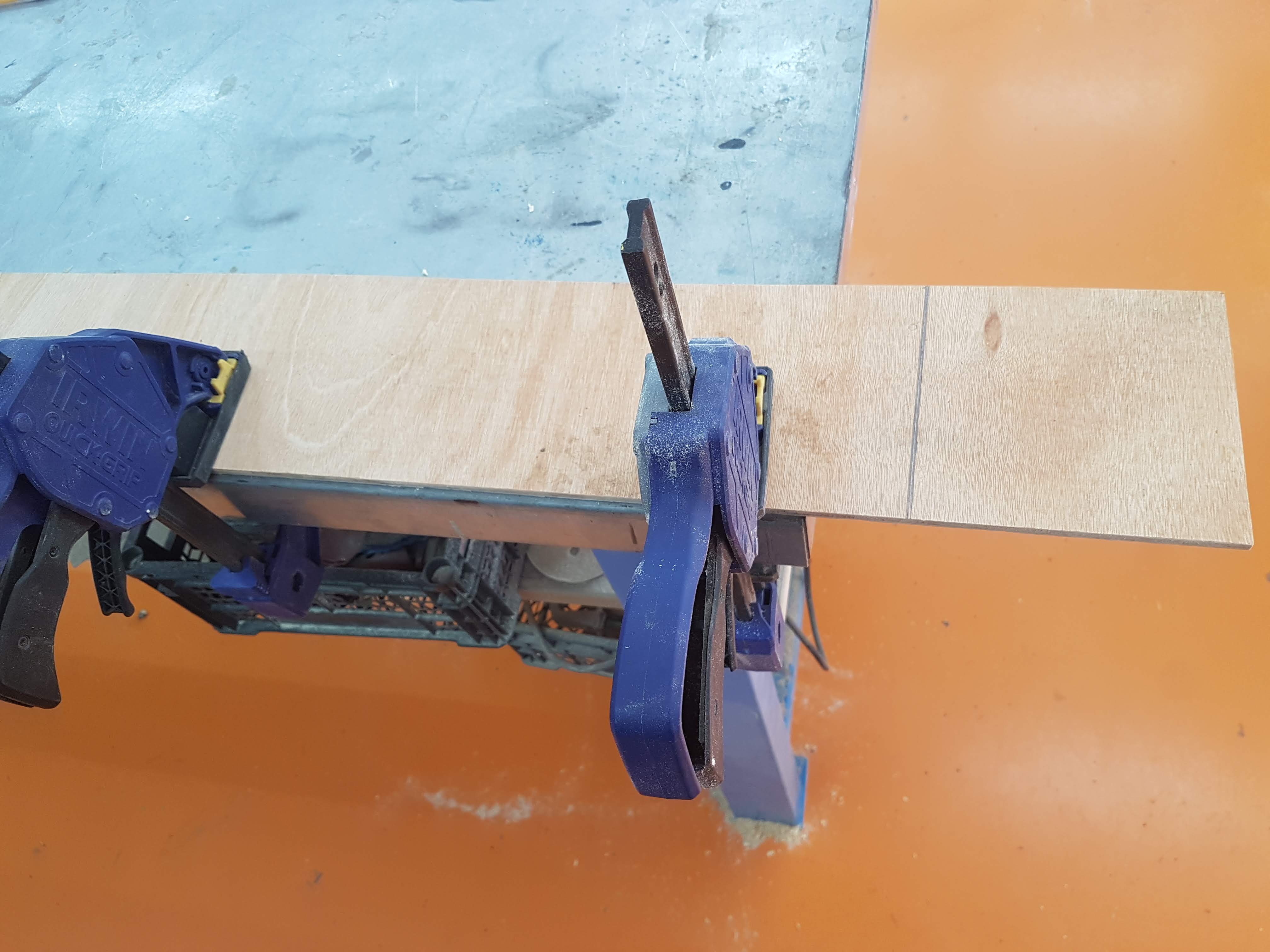 אחיזה של הלוח בקצה השולחן, כשקו החיתוך במרחק של 3-4 ס: